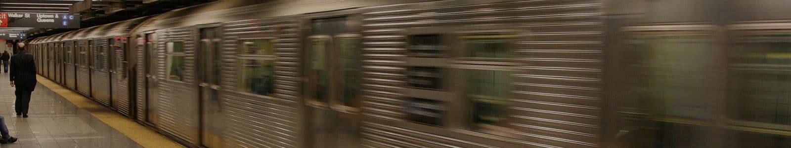 nyc train leaving the station while communters walk down the platform