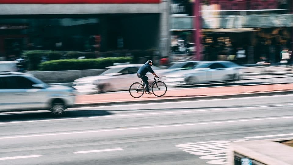 blurred image of an NYC cyclist riding on a sidewalk road divider