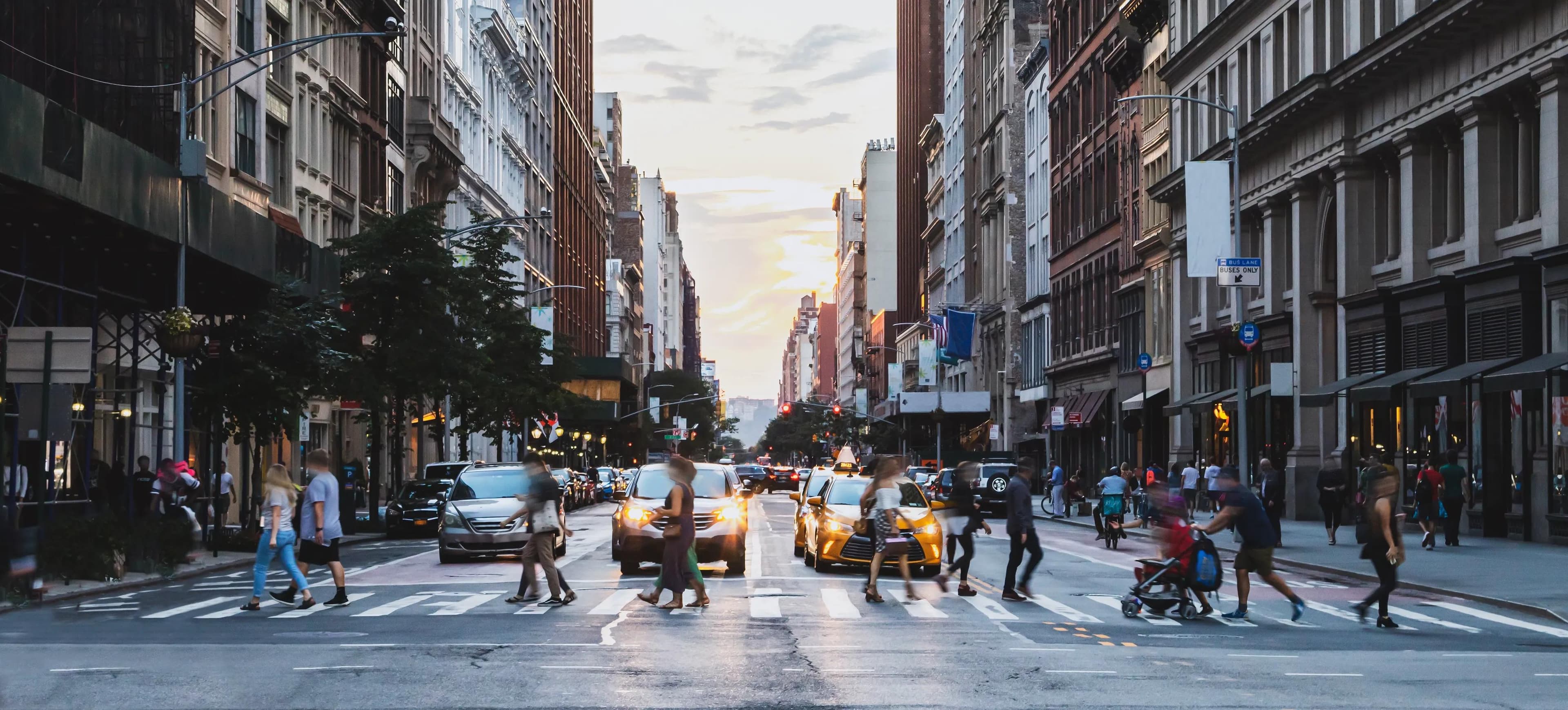 NYC pedestrians crossing a crosswalk while cars and taxis wait