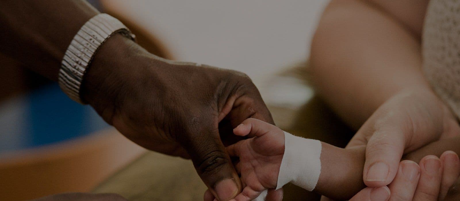 Parents holding their newborn baby's hand